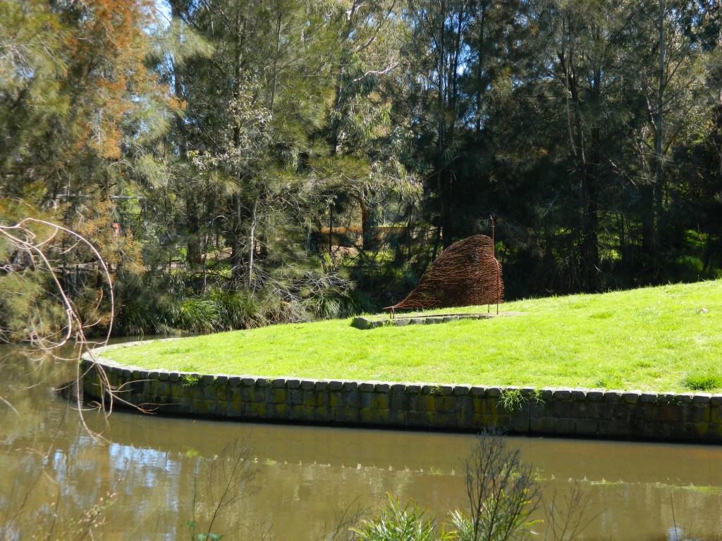 Heather B. Swann's sculpture, Horned Night Walker, shaped from thin iron bars, seen across the water.
