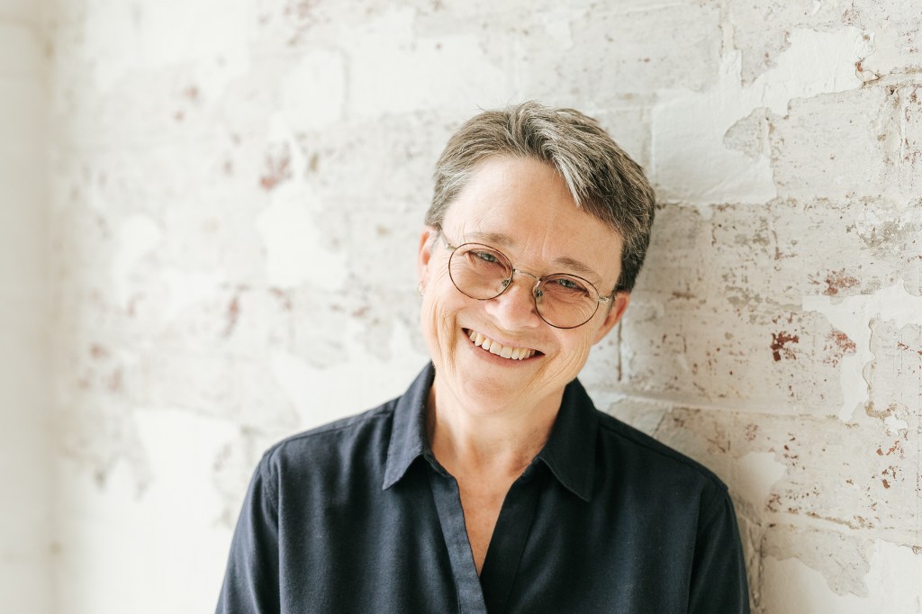 Portrait of Kelly against a while wall.